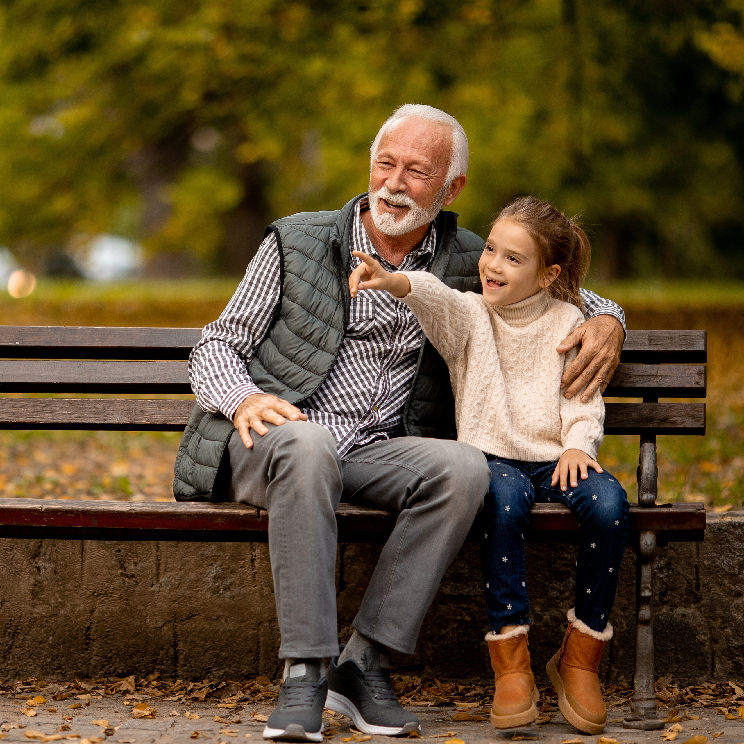Grandfather spending time with his granddaughter on bench in par